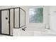 Modern bathroom with a glass-enclosed shower, standalone tub, and decorative privacy window, offering a luxurious feel at 1675 Bookhout Dr, Cumming, GA 30041