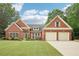 Charming brick home featuring a well-manicured lawn, mature trees, and a two-car garage at 1675 Bookhout Dr, Cumming, GA 30041
