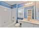 Blue bathroom with tub and shower combination, window, vanity, and toilet at 6275 Glen Oaks Ln, Atlanta, GA 30328