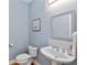 Charming powder room featuring a pedestal sink, decorative mirror, and soft blue walls at 6275 Glen Oaks Ln, Atlanta, GA 30328
