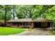 Ranch-style brick home featuring a covered carport and a lush, tree-filled front yard at 6470 Sherwood Trl, Austell, GA 30168