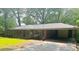 Sprawling red brick ranch-style home surrounded by lush greenery and a covered parking area at 6470 Sherwood Trl, Austell, GA 30168