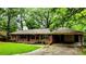 Charming brick ranch-style home with a covered carport and cozy front porch surrounded by mature trees at 6470 Sherwood Trl, Austell, GA 30168