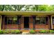 Front porch features black, ornate support columns and landscaping creating an inviting entrance to the brick home at 6470 Sherwood Trl, Austell, GA 30168