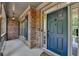 Inviting entryway featuring a classic blue front door, brick facade, and covered porch at 2725 Monet Dr, Cumming, GA 30041