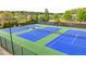 Bright blue and green community tennis courts surrounded by black fencing and mature trees at 2725 Monet Dr, Cumming, GA 30041