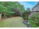 Backyard area with a small deck, lawn, mature trees, and landscape features at 3958 Windgrove Xing, Suwanee, GA 30024