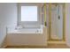 Bright bathroom featuring a soaking tub beneath a window, and a shower with gold trim at 3958 Windgrove Xing, Suwanee, GA 30024
