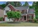 Charming two-story brick home featuring a black front door, a covered front porch, and manicured landscaping at 3958 Windgrove Xing, Suwanee, GA 30024
