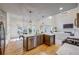 Eat-in kitchen includes stainless steel appliances, granite countertops, pendant lights, and an adjacent living room with fireplace at 3958 Windgrove Xing, Suwanee, GA 30024