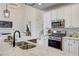 A modern kitchen features stainless steel appliances, white cabinets, granite countertops, and is adjacent to living room at 3958 Windgrove Xing, Suwanee, GA 30024