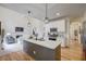 Open kitchen with stainless steel appliances, granite countertops, pendant lights, and an adjacent living room with fireplace at 3958 Windgrove Xing, Suwanee, GA 30024