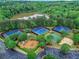 Aerial view showcasing tennis courts and sand volleyball surrounded by mature trees and parking at 3958 Windgrove Xing, Suwanee, GA 30024