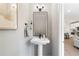 Modern powder room with a pedestal sink, stylish mirror, and elegant decor with the kitchen in the background at 409 Retreat Ln, Canton, GA 30114
