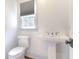 A well-lit bathroom features a pedestal sink and toilet illuminated by natural light from the window at 3485 Aubusson Trce, Johns Creek, GA 30022