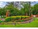 Well manicured entryway with brick pillars, iron gate, lush shrubbery, and colorful flower beds at 27306 Plantation Ne Dr, Atlanta, GA 30324