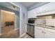 Modern kitchen featuring stainless steel appliances, granite counters, and white cabinetry, plus adjacent bonus room at 27306 Plantation Ne Dr, Atlanta, GA 30324