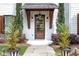 Close-up of a stylish front door with a covered porch, wooden accents, and elegant landscaping at 3920 Cash Lndg, Marietta, GA 30066