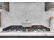 Modern gas cooktop on marble countertops with a gray backsplash and cabinets at 3920 Cash Lndg, Marietta, GA 30066