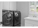 Functional laundry room features modern washer and dryer units, sink, storage, and natural light at 109 Hawks Bnd, Canton, GA 30115