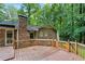 A large wooden deck with railing sits off the back of the house with a lush green forest in the background at 4293 Smithsonia Dr, Tucker, GA 30084