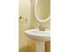Pedestal sink and round mirror in a bathroom with soothing yellow walls at 786 Brookside Parc Ln, Avondale Estates, GA 30002