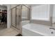 Bathroom featuring a bathtub, glass enclosed shower, and window for natural light at 9913 Stretford Rd, Douglasville, GA 30135