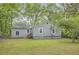 Rear view of house with gray siding and a grassy yard surrounded by trees at 1723 Ritcherson Se St, Marietta, GA 30060