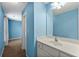 Bright bathroom with blue walls, a single sink vanity, a mirror, and adjacent bedroom space at 5826 Sarazen Trl, Douglasville, GA 30135