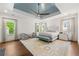 This main bedroom features blue tray ceiling, ceiling fan, hardwood floors and large windows overlooking greenery at 4005 N Stratford Ne Rd, Atlanta, GA 30342