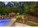 Landscaped backyard featuring an in-ground pool, garden with stone steps, and tranquil lighting at 2439 Huntington Park Nw Dr, Acworth, GA 30101
