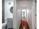 Hallway featuring hardwood flooring, leading to a bathroom with modern vanity and round mirror at 5101 Rockbridge Rd, Stone Mountain, GA 30088