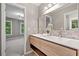Bathroom featuring a double vanity, a decorative mirror, and a doorway to bedroom at 515 Old Chartwell Xing, Alpharetta, GA 30022