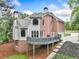 Exterior view of a brick and vinyl sided home with a deck overlooking a landscaped yard and driveway at 515 Old Chartwell Xing, Alpharetta, GA 30022