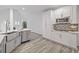 Well-lit kitchen features white cabinets, stainless appliances, and a view to the great room fireplace at 515 Old Chartwell Xing, Alpharetta, GA 30022