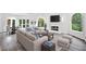 Open concept living room with plush furniture, fireplace, and light gray wood floors leading to the dining area at 515 Old Chartwell Xing, Alpharetta, GA 30022