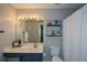 Bathroom with blue vanity, large mirror with lighting, and a shelf next to the toilet at 1575 Kilmington Ct, Alpharetta, GA 30009