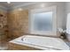 A tiled bathroom features a drop-in bathtub with a window and a walk-in shower at 3253 Cates Ne Ave, Brookhaven, GA 30319