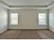 Carpeted bedroom featuring two windows and a tray ceiling at 3658 Hidden Valley Cir, Lawrenceville, GA 30044