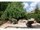 Outdoor patio area with comfortable seating around a stone fire pit, shaded by a weeping tree at 4231 Shamans Dr, Marietta, GA 30062