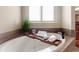 Relaxing bathtub with a wooden tray, a book, and a glass of wine next to a sunlit window at 4231 Shamans Dr, Marietta, GA 30062