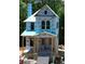 Two-story house under construction with a covered porch and windows ready for installation at 11825 Serenbe Ln, Chattahoochee Hills, GA 30268