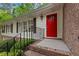 Close up of a bright red front door with sidelight, black iron railing, and brick steps at 2488 Fontainebleau Dr, Dunwoody, GA 30360