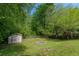Lush backyard featuring a shed and fire pit, surrounded by mature trees at 1287 Peninsula Trce, Lawrenceville, GA 30044