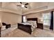 Spacious bedroom featuring a large bed, tray ceilings, fan, and abundant natural light from the windows at 3160 Bailey Cove Ct, Dacula, GA 30019