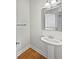 Simple powder room featuring a pedestal sink, hardwood floors, a chrome framed mirror and modern lighting at 7155 Homestead Rd, Rex, GA 30273