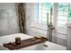 Relaxing bathtub with a handheld shower fixture and a stylish tray showcasing spa accessories at 917 Gaylemont Cir, Decatur, GA 30033