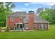 Brick home's backyard with a covered patio, lush lawn, and mature trees at 2498 Highway 212, Covington, GA 30016