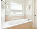 Bathroom featuring a jetted tub with tile surround and a frosted window at 424 Melrose Ave, Decatur, GA 30030