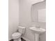Bathroom featuring a pedestal sink with a decorative mirror and a toilet, showcasing a clean and modern design at 339 Elgin Dr, Lawrenceville, GA 30045